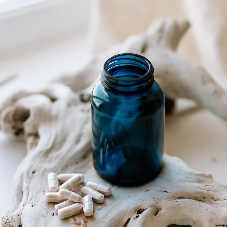 Marine-based hair growth supplement tablets beside a deep blue bottle